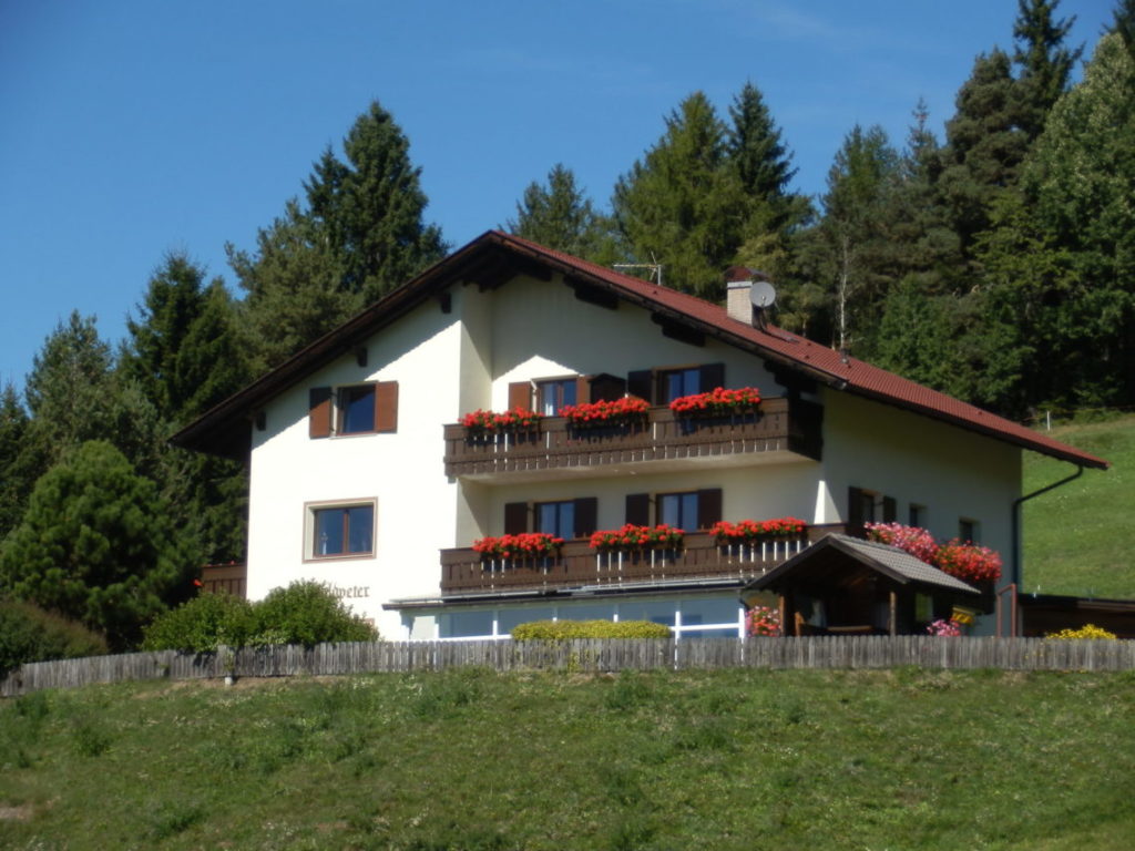 Casa con due balconi circondata da prati e boschi