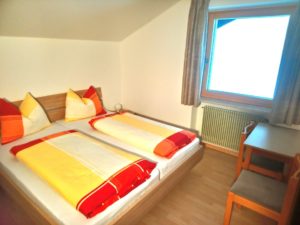 Doppelbett vor Fenster mit Blick auf Grasfläche
